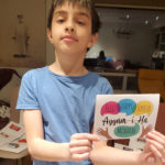 Anis holding up one of the cards he helped prepare for his classmates.