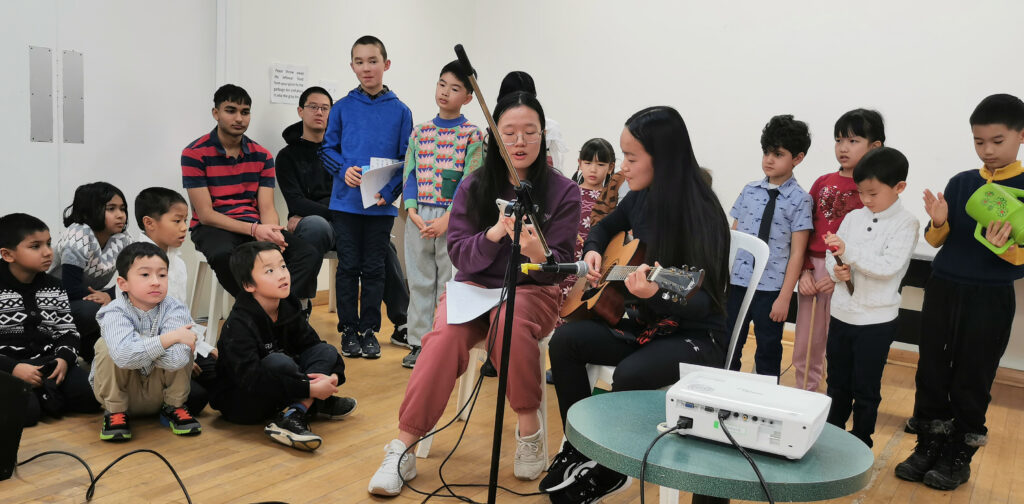 Ruhi book 1 participants present a song about friendship at the community gathering to their families and to the children gathered around them.